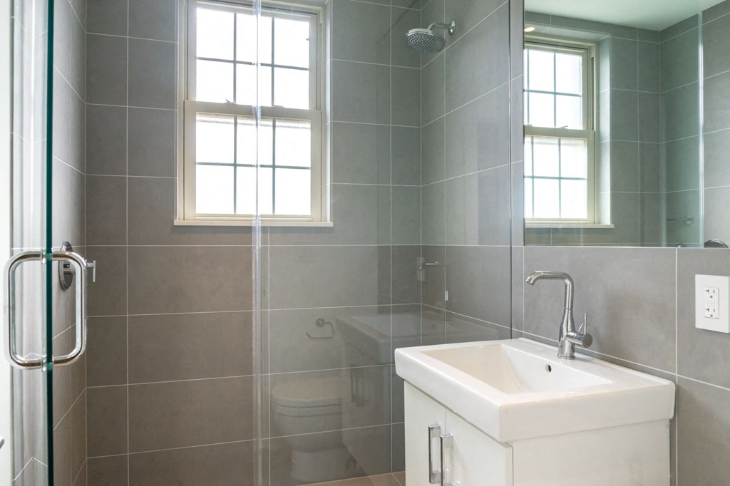 a bathroom with a shower and a sink and a window