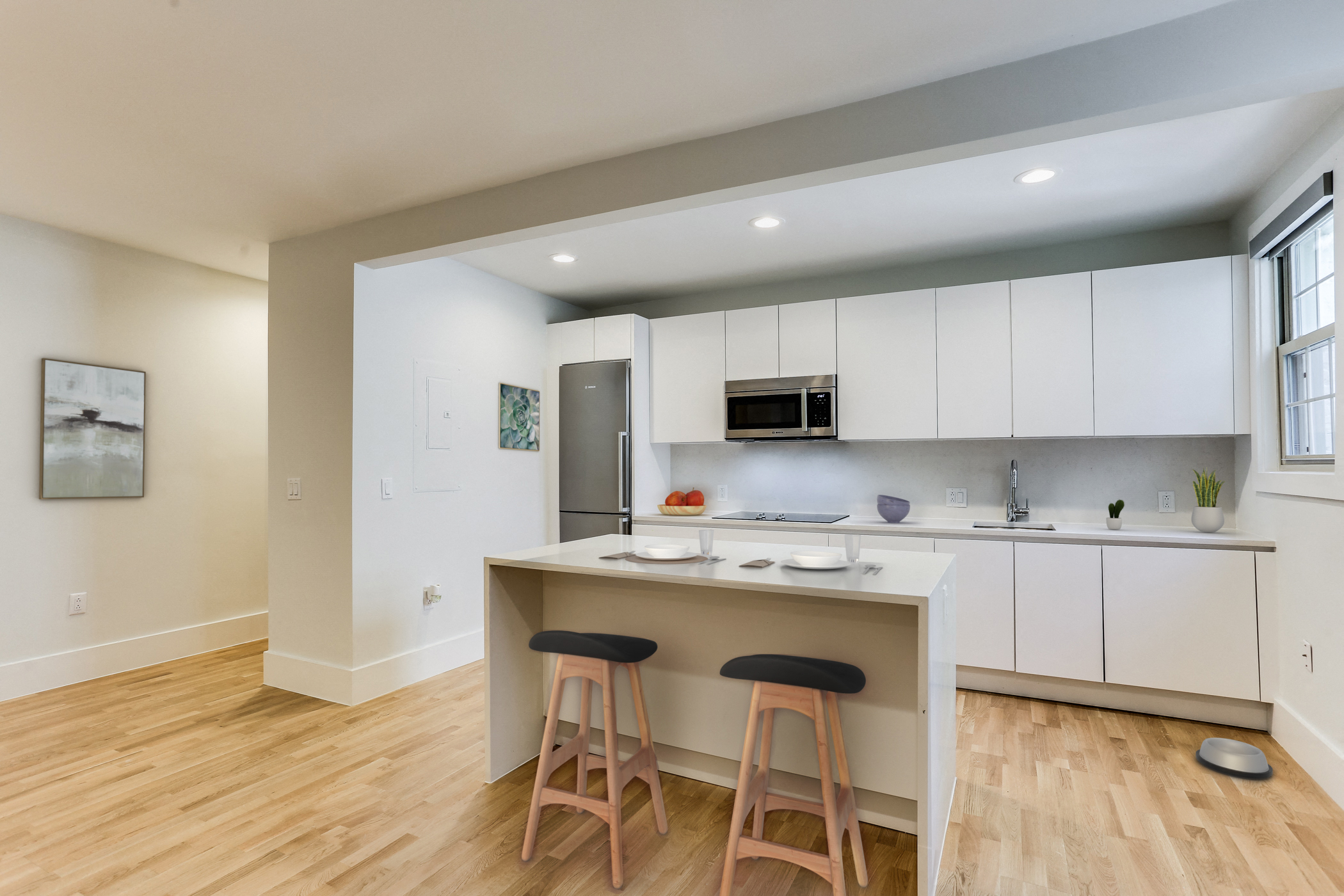 a kitchen with white cabinets and a bar with two stools