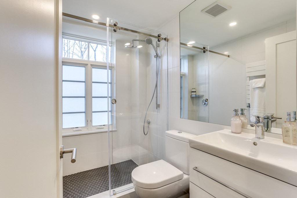 a white bathroom with a shower toilet and sink