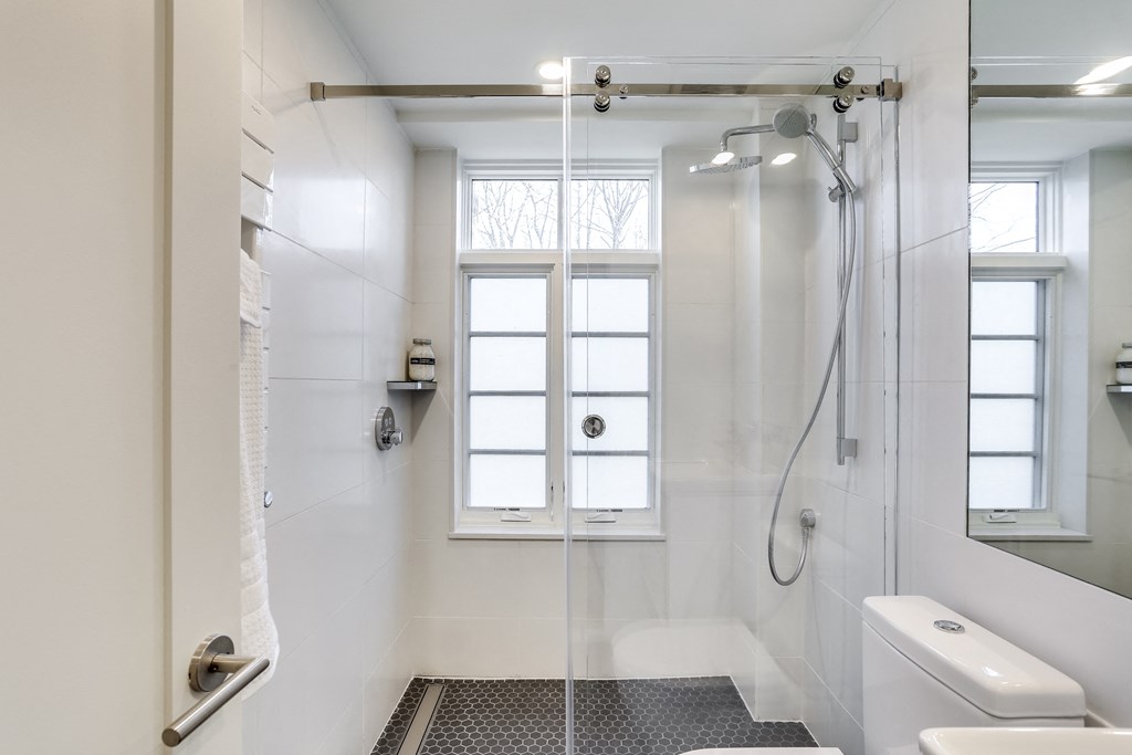 a white bathroom with a shower and a window