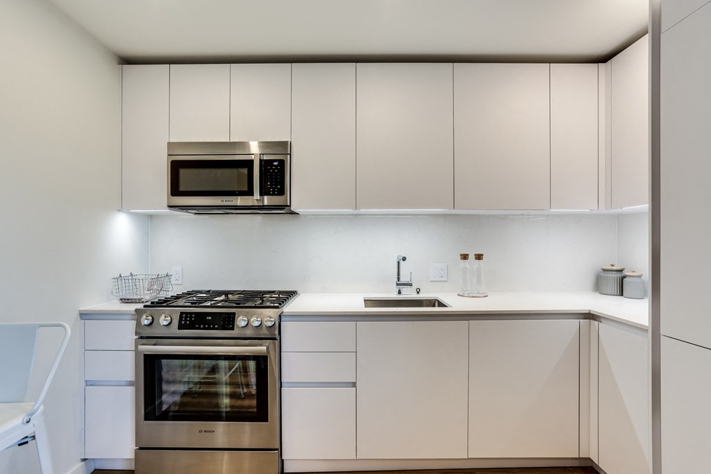 a modern kitchen with white cabinets and stainless steel appliances