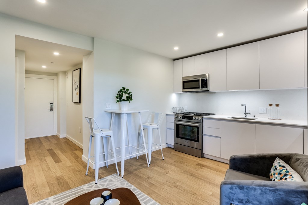 a living room and kitchen with white cabinets and a table and chairs