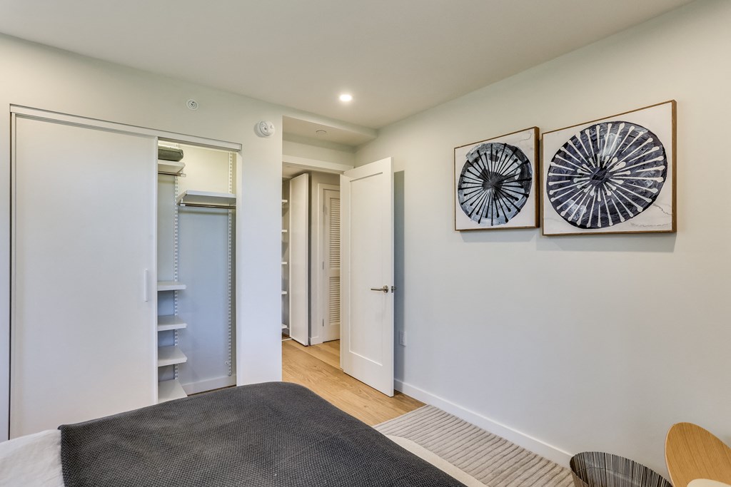 a bedroom with a closet and a bed and two paintings on the wall