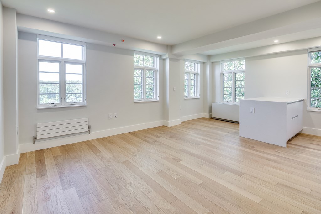 a living room with white walls and wooden floors and a white cabinet