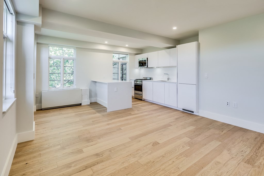 an empty kitchen with white cabinets and a large window