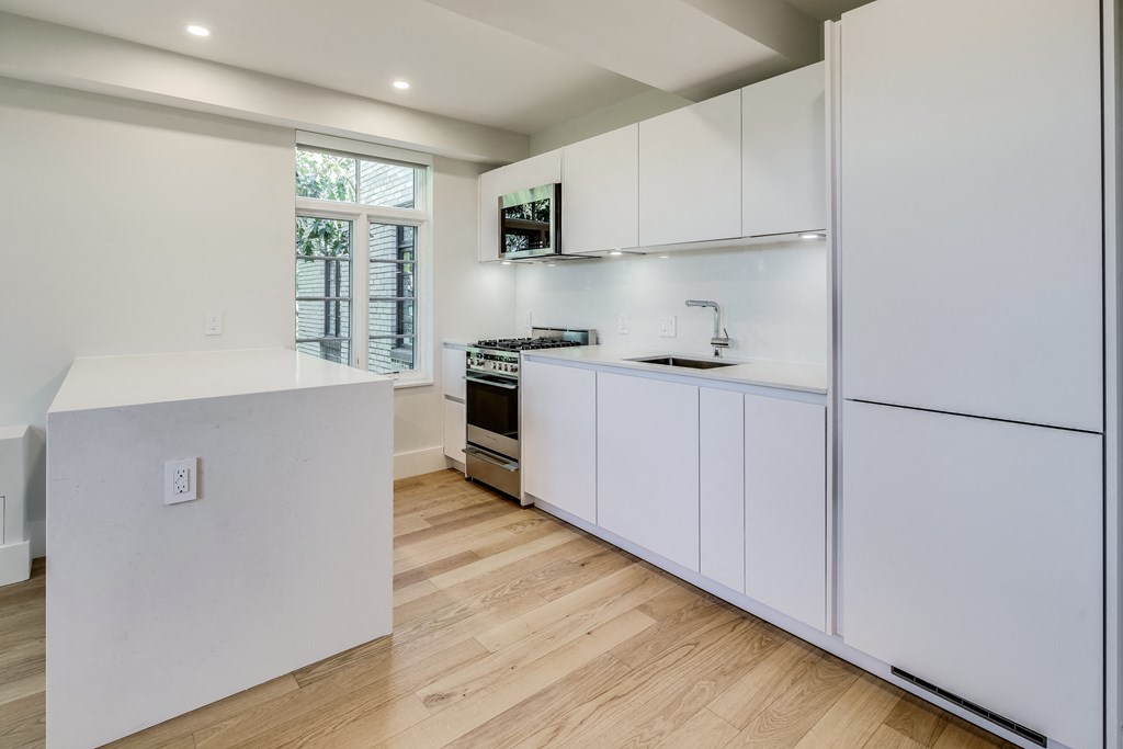 a white kitchen with white cabinets and a window