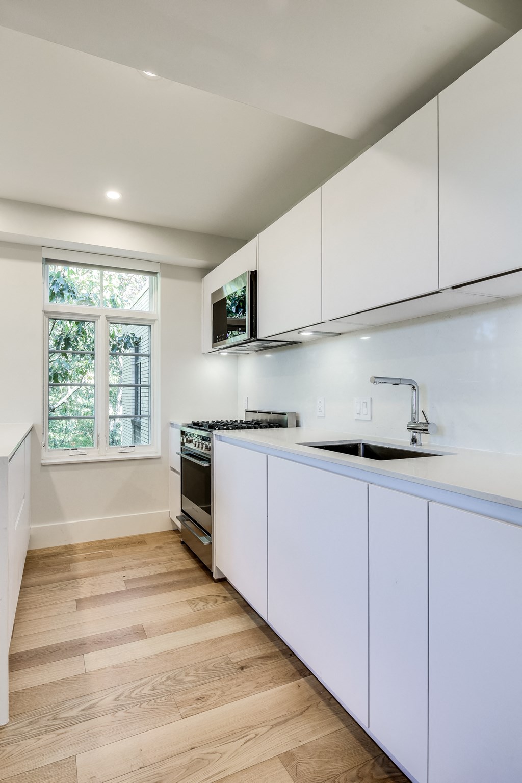 a kitchen with white cabinets and a sink and a window