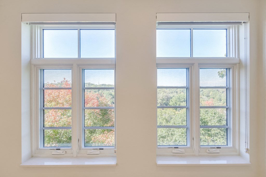 two windows in a room with a view of trees