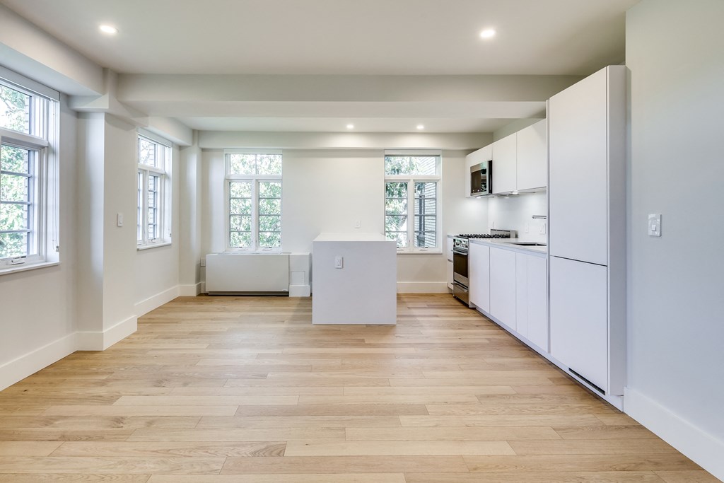 a white kitchen with white cabinets and white appliances and wood floors