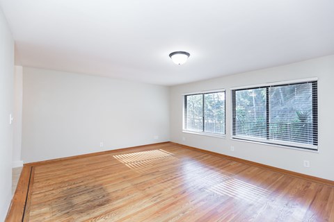 A room with wooden flooring and a window with blinds.