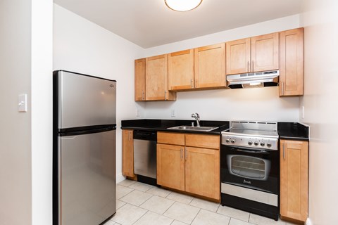 A kitchen with wooden cabinets and black countertops.