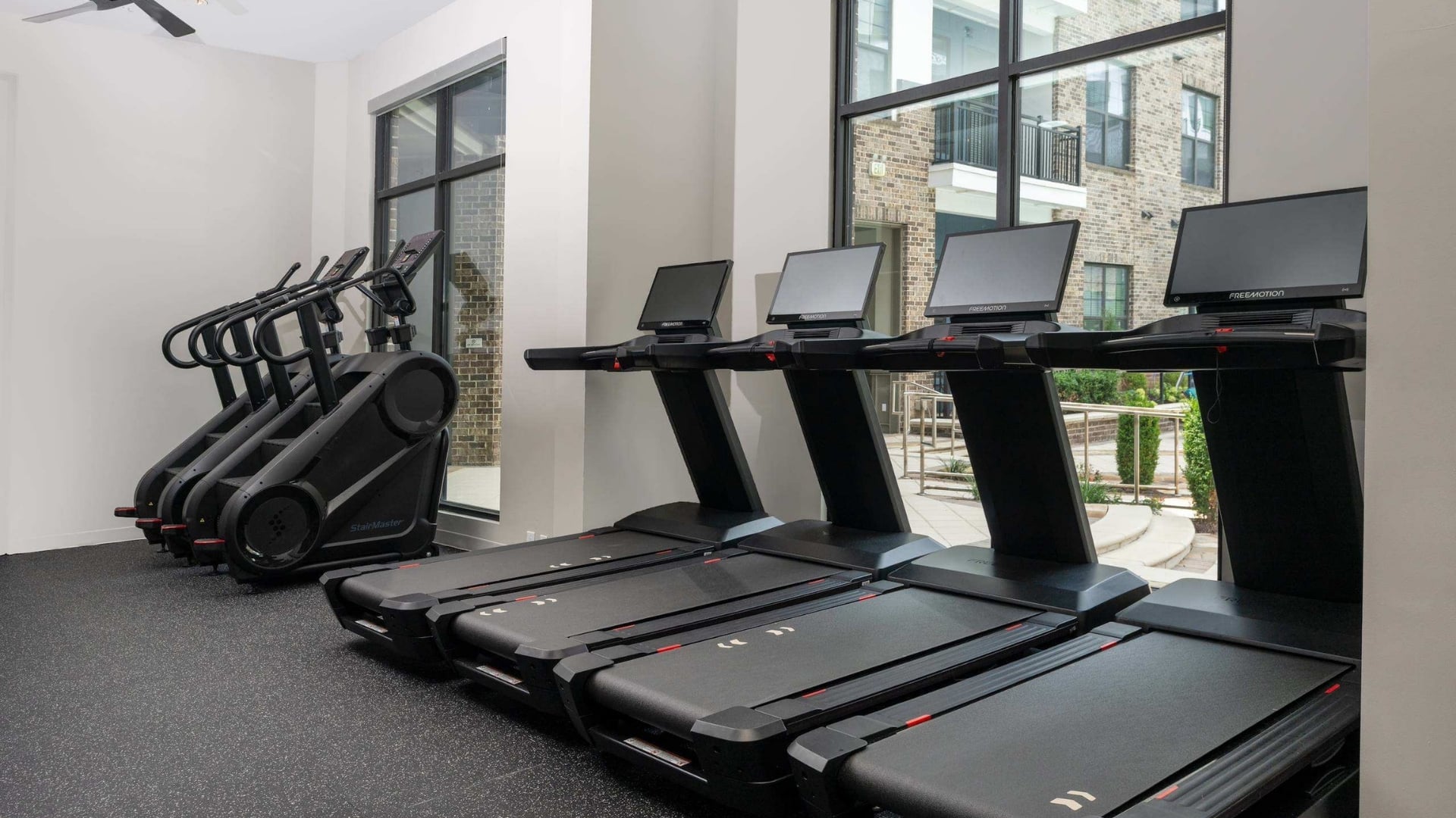 A row of treadmills and elliptical machines in a gym.