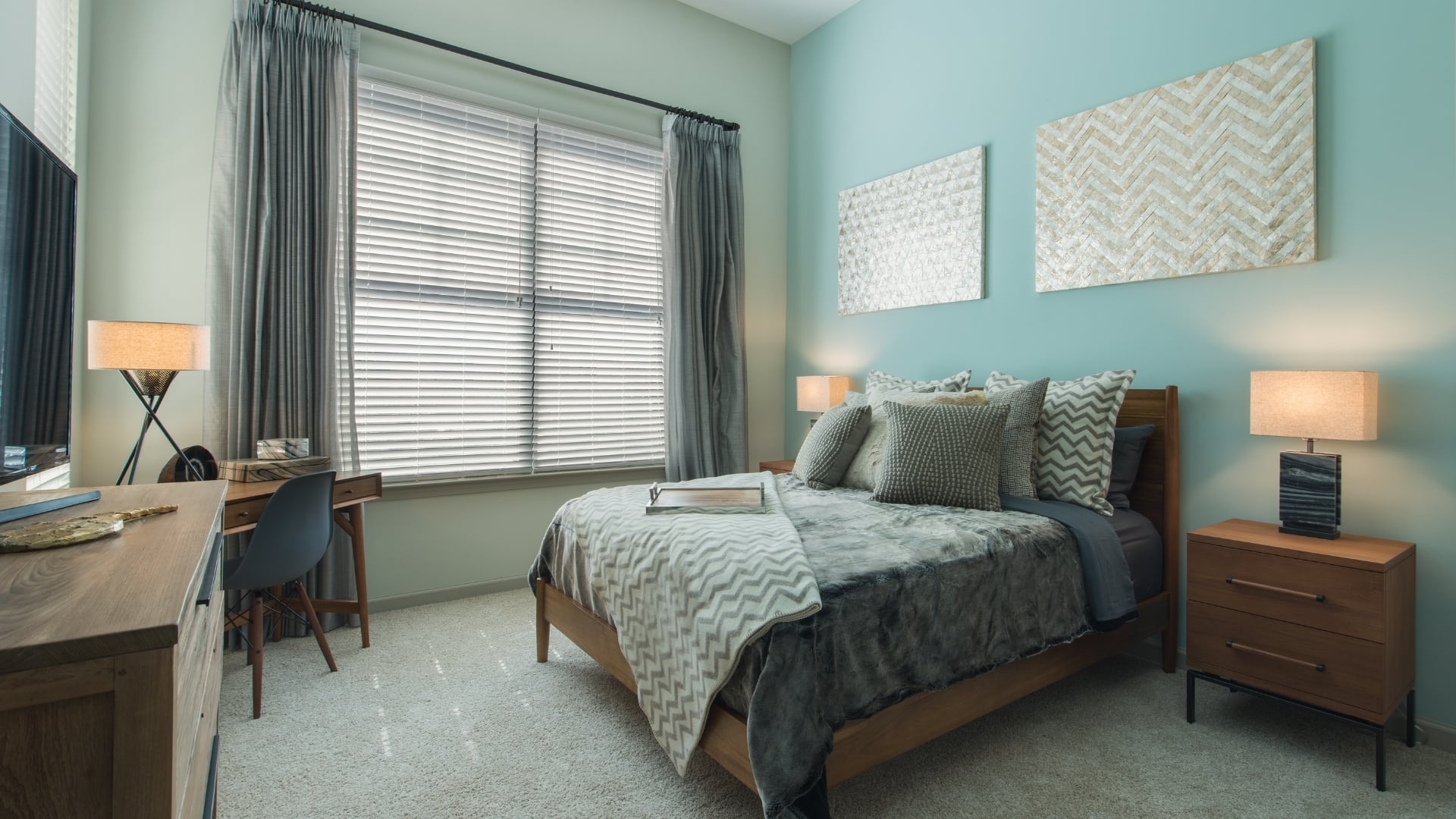 A bedroom with a large bed, a desk, and a chair.