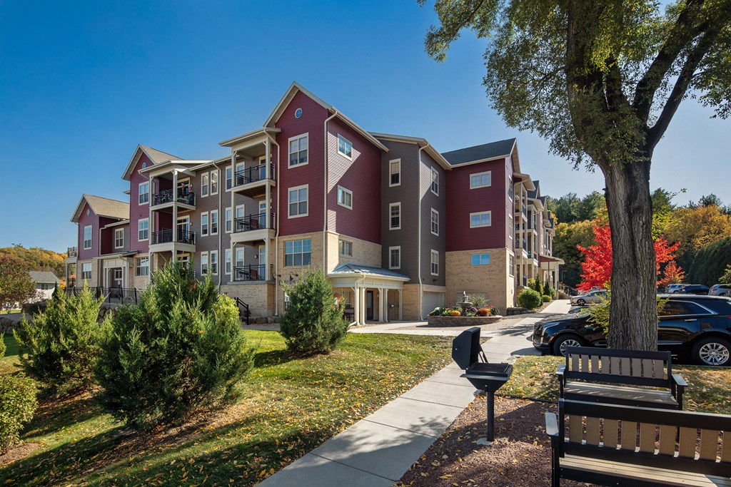 an apartment building with a sidewalk and a park bench