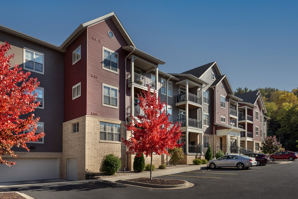 an apartment building with red trees in front of it