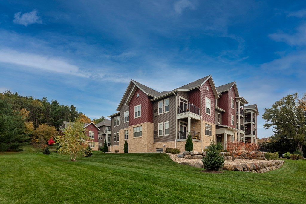 a large apartment building with green grass and a blue sky