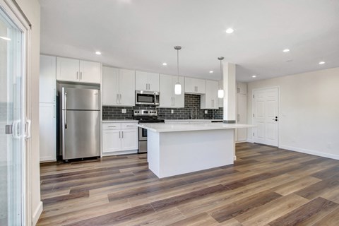 A modern kitchen with a stainless steel refrigerator and a white island.