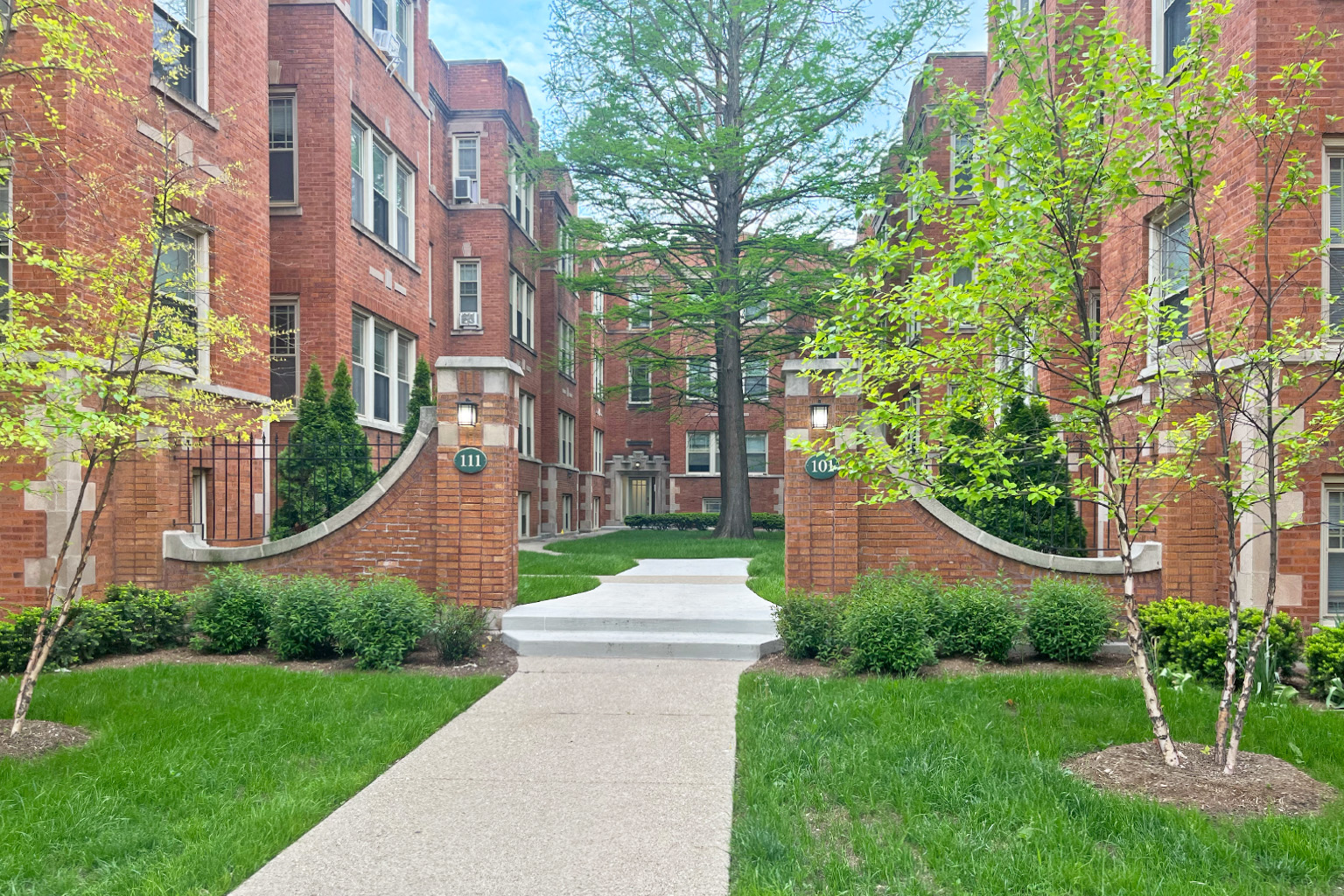 A pathway leads through a green lawn to a brick building.