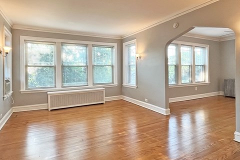 A room with wooden floors and a window with blinds.