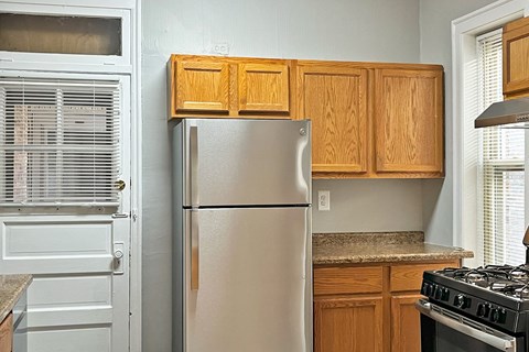A kitchen with a stainless steel refrigerator and wooden cabinets.