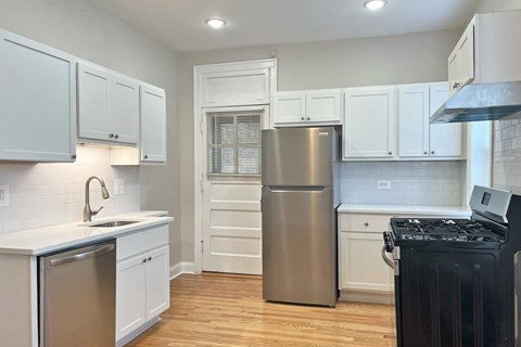 A kitchen with white cabinets and a stainless steel refrigerator.