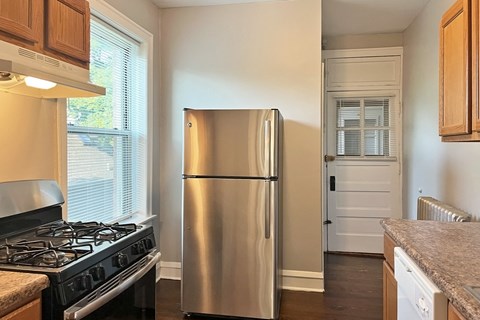 A stainless steel refrigerator in a kitchen with wooden cabinets.
