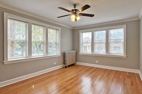 A room with a ceiling fan and wooden flooring.