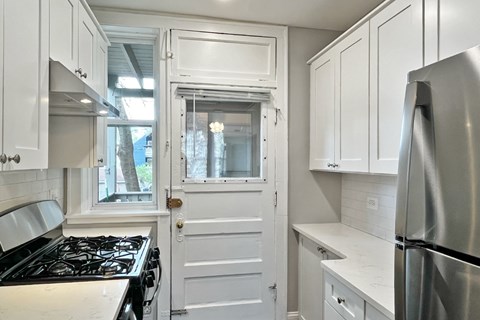 A kitchen with white cabinets and a stainless steel refrigerator.