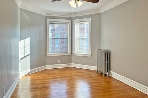 A room with a ceiling fan and a radiator on the floor.