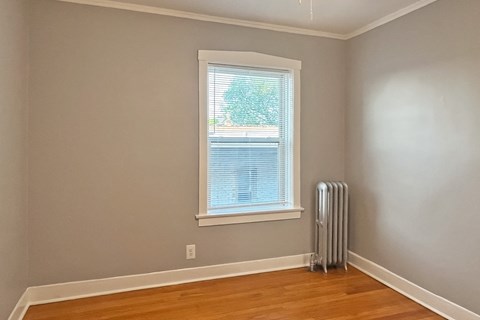 A room with a window and a radiator on the floor.