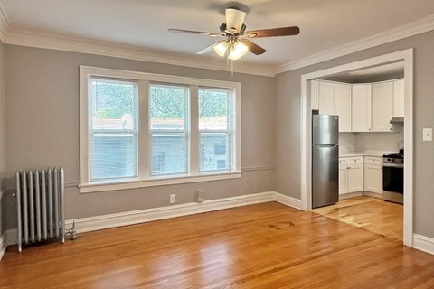 A room with a ceiling fan and a window with blinds.