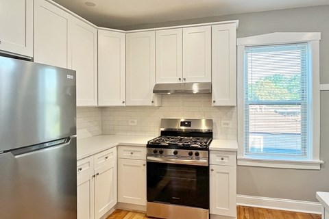 A kitchen with white cabinets and a stainless steel refrigerator.