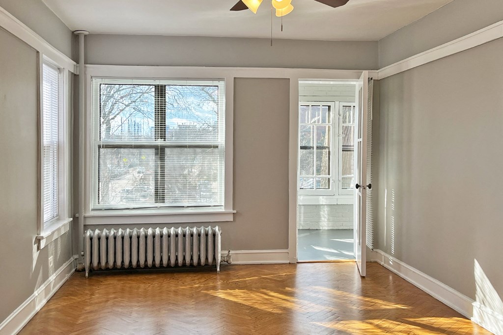 A room with a window, a radiator, and a wooden floor.