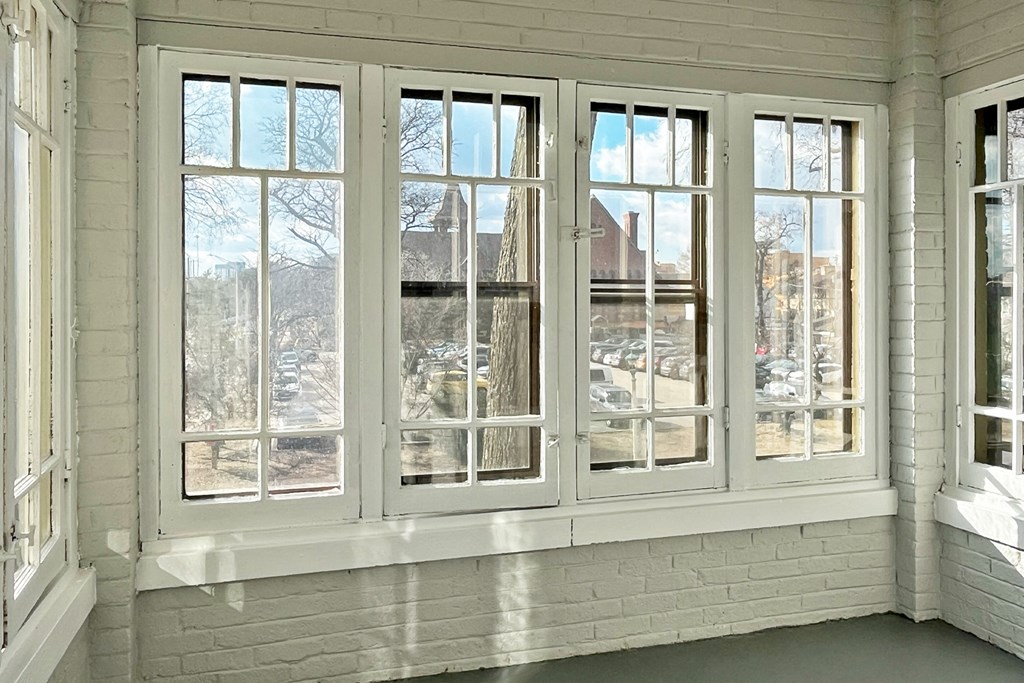 A white room with a large window showing a view of a parking lot.