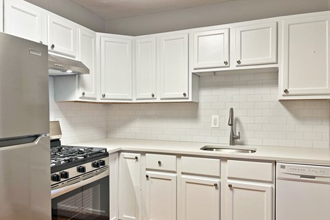 A kitchen with white cabinets and a stove top oven.