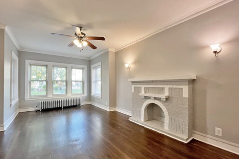 A living room with a fireplace and a ceiling fan.