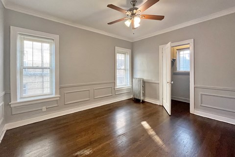 A room with a ceiling fan and wooden floors.