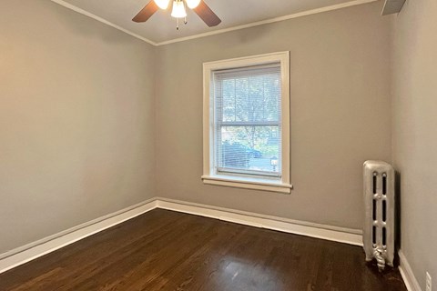 A room with a window and a fan on the ceiling.