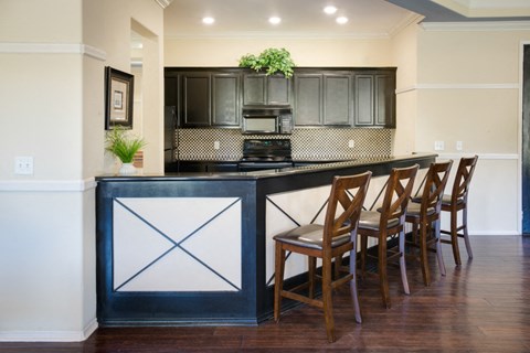 A kitchen island with a black and white design sits in front of a counter with four chairs.