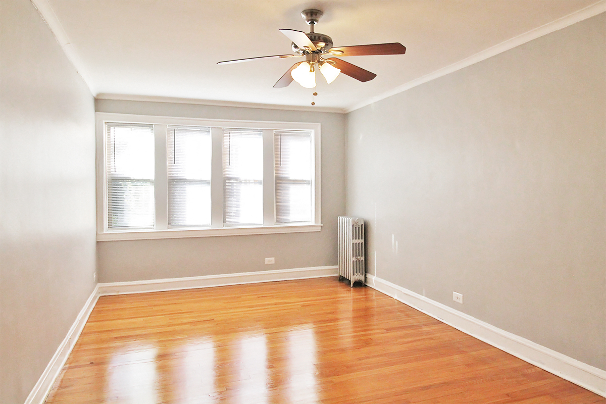 an empty room with wood floors and a ceiling fan