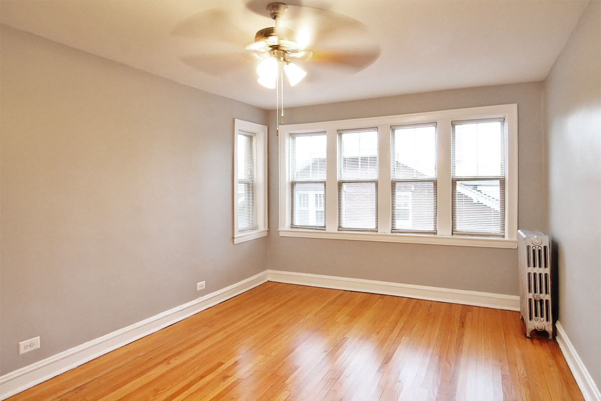 an empty living room with wood floors and a ceiling fan
