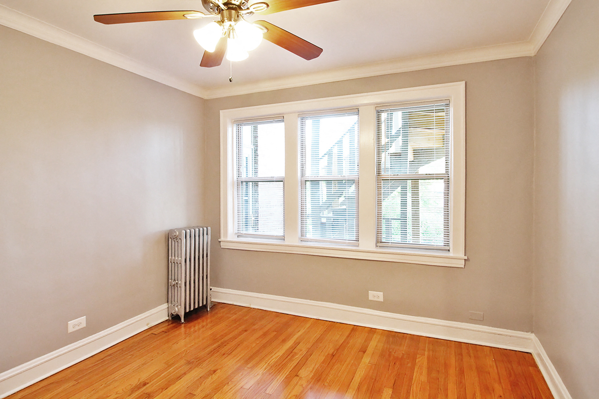 an empty room with a ceiling fan and three windows