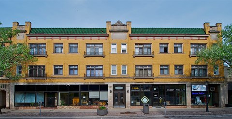 a yellow building with a green roof on a city street