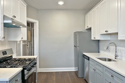 A kitchen with white cabinets and a black stove top.