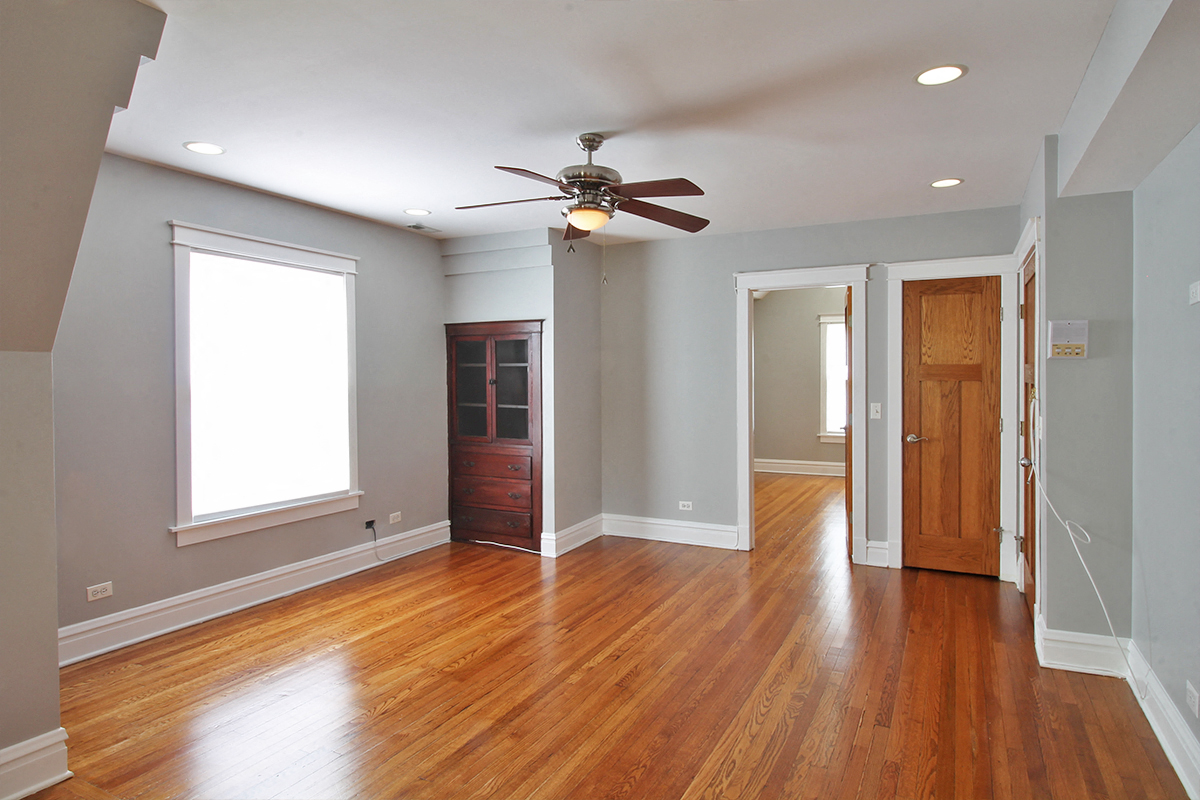 an empty living room with wood floors and a ceiling fan