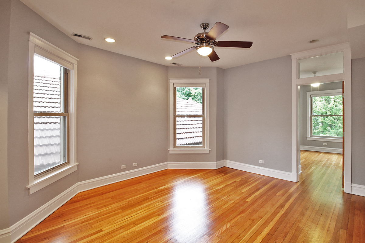 an empty living room with wood floors and a ceiling fan