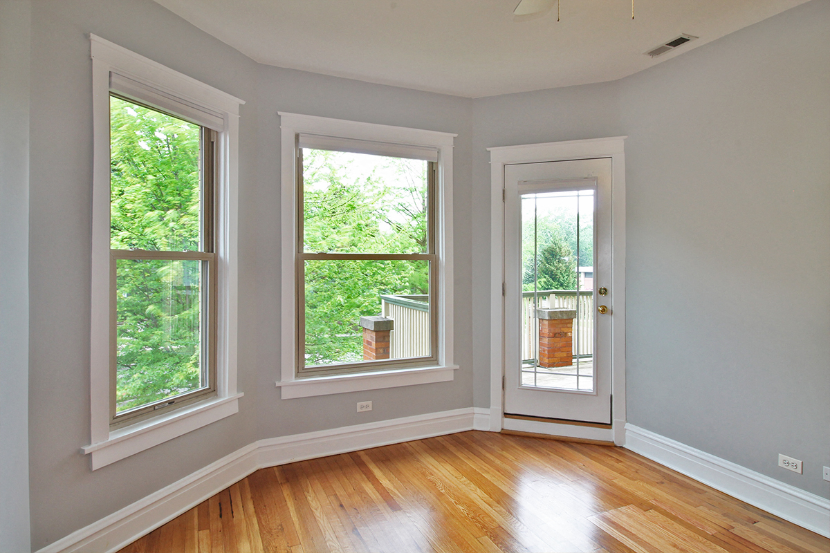 an empty room with three windows and a door to a balcony