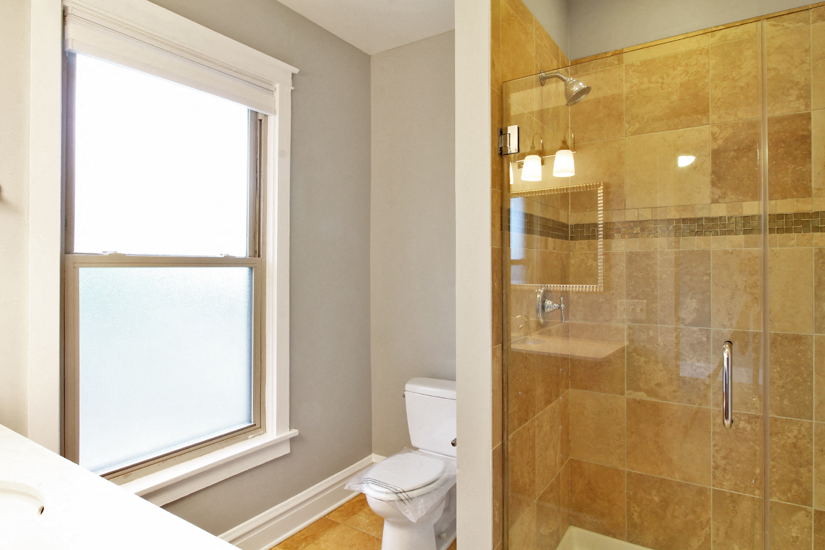a bathroom with a shower toilet and a window