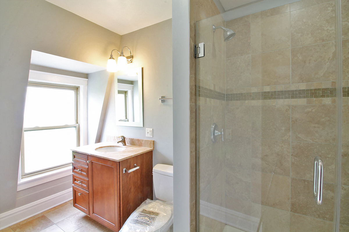 a bathroom with a shower and a sink and a window