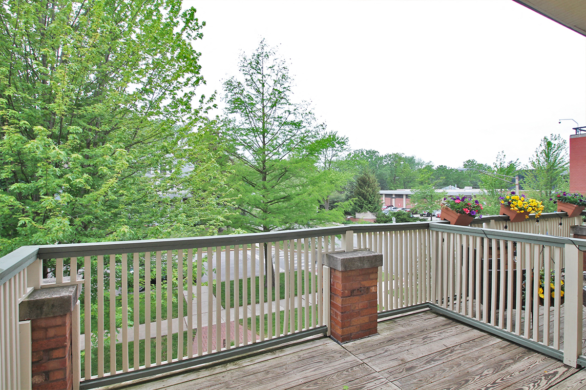 the deck has a view of the neighborhood and the trees